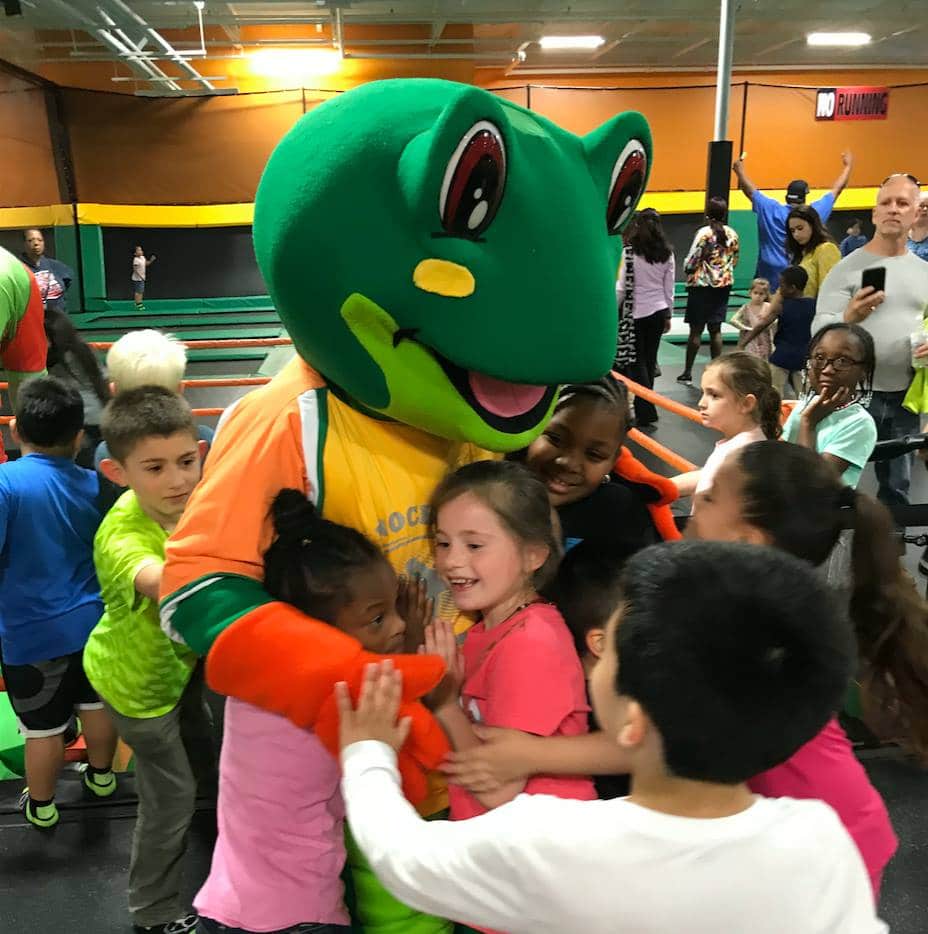 Rockin’ Jump Trampoline Parks Indoor playground frog mascot hugging children at trampoline park